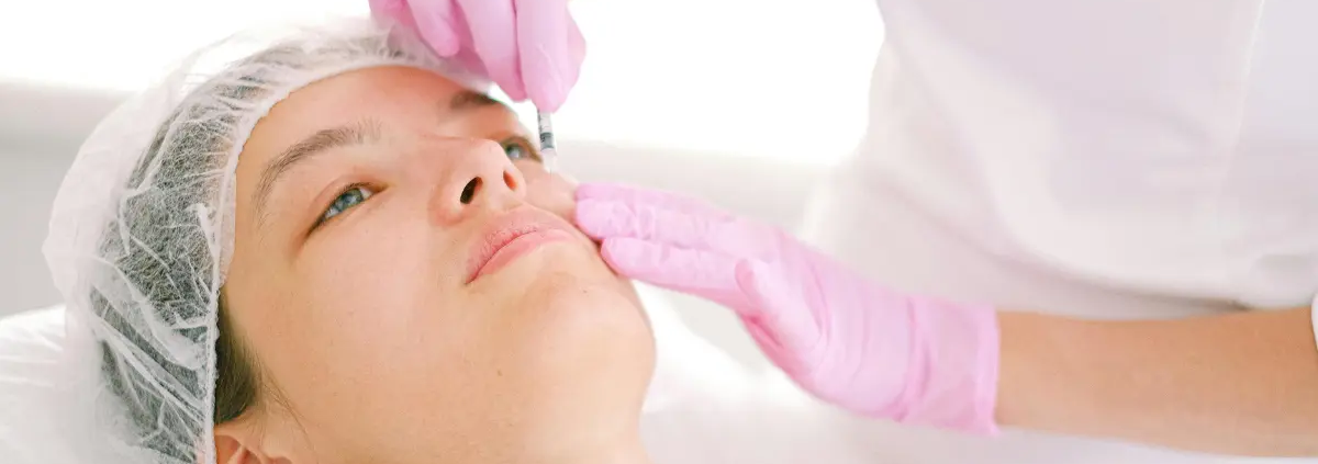 Donna riceve iniezione di tossina botulinica sul viso da un medico con guanti rosa